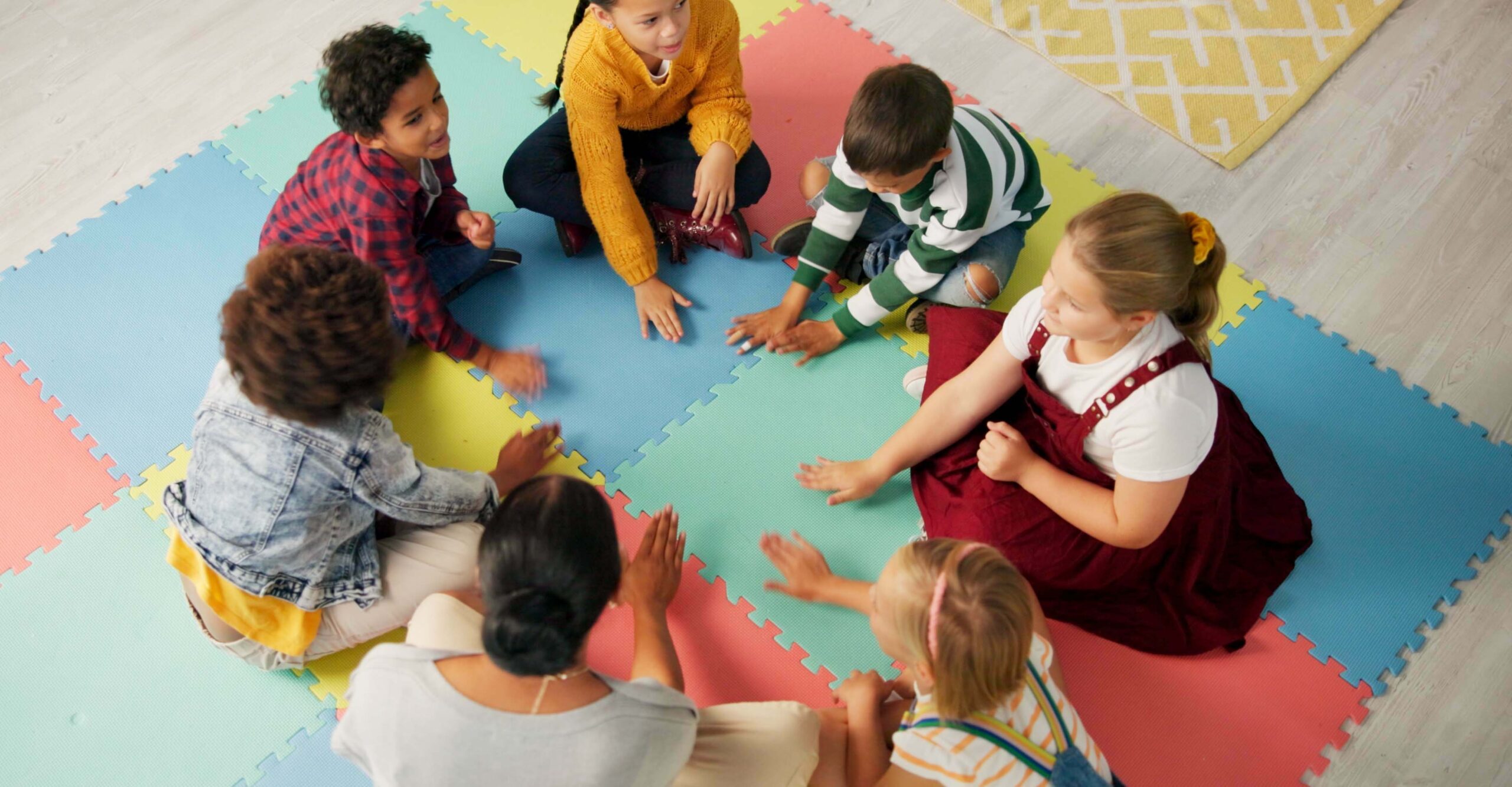 School, kids and teacher with game in circle for child development, activity and growth. High angle, hands and playful student on mat in kindergarten for sensory learning, creative skill or education
